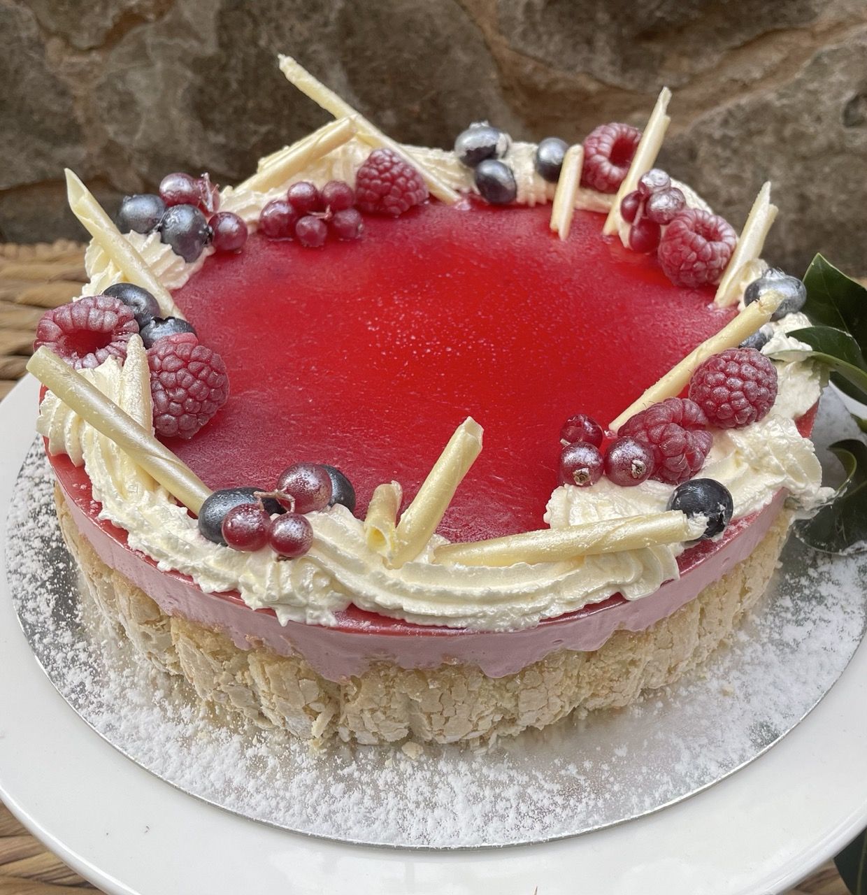 Whole red-glazed berry celebration cake on a white stand